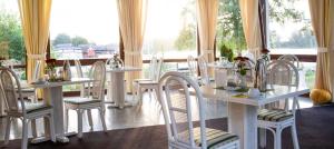 une salle à manger avec des tables et des chaises blanches ainsi qu'une fenêtre dans l'établissement Hotel Seestern, à Röbel