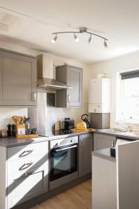 kuchnia z szarymi i białymi urządzeniami oraz oknem w obiekcie Little Edge: Bright and Modern Central Apartment w mieście Berwick-upon-Tweed