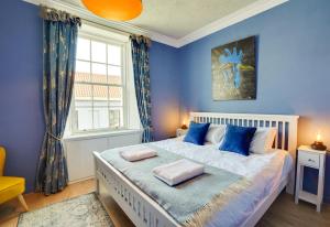 a bedroom with blue walls and a bed with blue pillows at Little Edge: Bright and Modern Central Apartment in Berwick-Upon-Tweed
