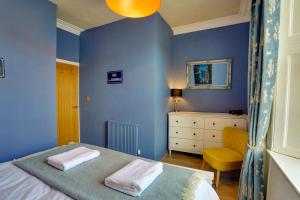 a blue bedroom with a bed and a yellow chair at Little Edge: Bright and Modern Central Apartment in Berwick-Upon-Tweed