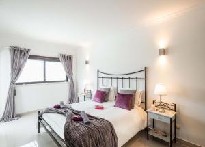 een slaapkamer met een groot bed met paarse kussens bij Villa Antiqua by Algarve Vacation in Albufeira