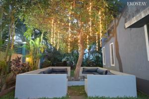 a patio with two couches and a tree with lights at EKO STAY (Gold) - BLUE PEBBLE VILLA in Lonavala
