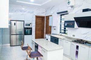 uma cozinha branca com um balcão e cadeiras em The Serenity Villa em Lekki