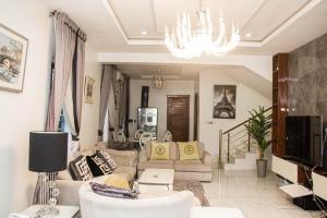 uma sala de estar com um sofá e um lustre em The Serenity Villa em Lekki