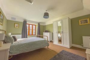um quarto com uma cama com paredes verdes e uma janela em Spacious-Rustic Cottage-Dog Friendly-w log burner em Worle