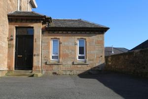 a brick building with a black door and two windows at Inverkar Mews Cottage, Ayr in Ayr