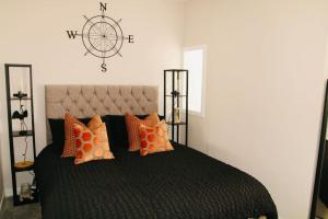 a bedroom with a large black bed with orange pillows at Inverkar Mews Cottage, Ayr in Ayr