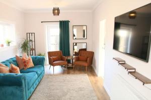 a living room with a blue couch and two chairs at Inverkar Mews Cottage, Ayr in Ayr