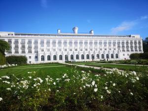 een groot wit gebouw met een bloemenveld bij Apartment near Baltic Sea in Jūrmala