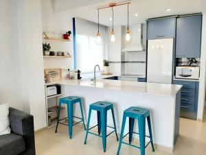 uma cozinha com três bancos azuis num balcão de cozinha em Big terrace in modern apartment close to the beach em Oropesa del Mar