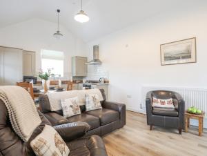 a living room with a leather couch and a dining room at Ty Den in Caernarfon