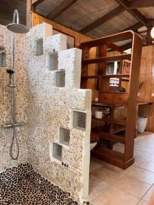 a bathroom with a shower with a wall of rocks at My Mountain Home in Taravao