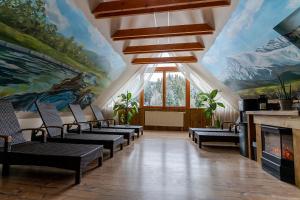 a room with chairs and a fireplace with a painting at Hotel Strachanovka - Jánska Koliba in Liptovský Ján