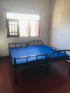 a bedroom with a blue bed with a window at Kandy Mount View hotel in Peradeniya