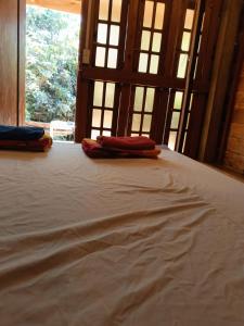 a bed with two pillows on it in a room with windows at FamilyHouse & Trekking in Banlung