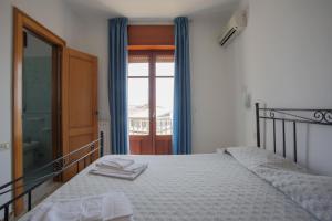 a bedroom with a bed with blue curtains and a window at Hotel Bolivar in Marina di Camerota