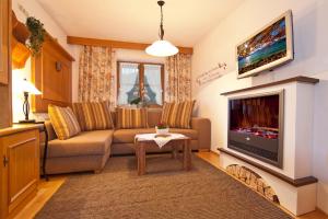 uma sala de estar com um sofá e uma televisão de ecrã plano em Ferienwohnungen Zum Baur em Krün