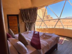 a bedroom with a bed and a large window at Wadi Rum Desert Bedouins in Wadi Rum