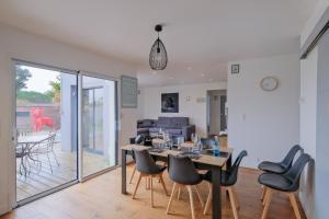 a dining room and living room with a table and chairs at Chez Arnold - Maison à moins dun km de la plage in La Turballe