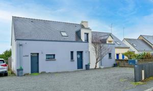 a white house with blue doors in a parking lot at Chez Arnold - Maison à moins dun km de la plage in La Turballe