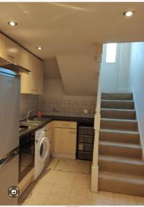 eine Küche mit einer Treppe, die zu einer Waschküche führt in der Unterkunft Tranquil Haven: A Cozy Retreat for Four in London