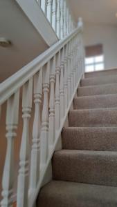 eine Treppe mit weißem Geländer in einem Haus in der Unterkunft Tranquil Haven: A Cozy Retreat for Four in London