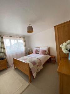 Schlafzimmer mit einem Bett mit rosa Kissen und einem Fenster in der Unterkunft ROSE COTTAGE in Ryde