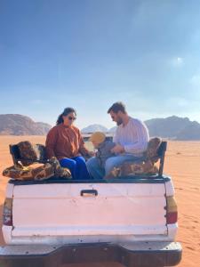 three people sitting on the back of a truck in the desert at Wadi Rum Desert Bedouins in Wadi Rum