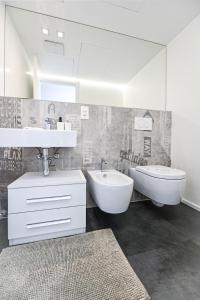 een witte badkamer met een wastafel, een toilet en een wastafel bij Lake View Suite Melide in Melide