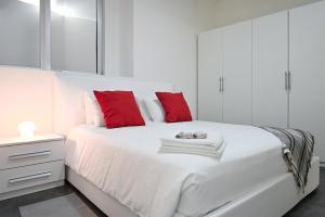 una camera bianca con un grande letto bianco con cuscini rossi di Lake View Suite Melide a Melide
