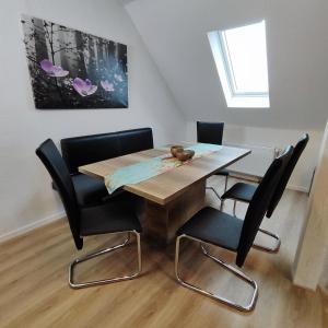 a dining room table with black chairs and a painting at Ferienwohnungen NordseeStern in Burhave
