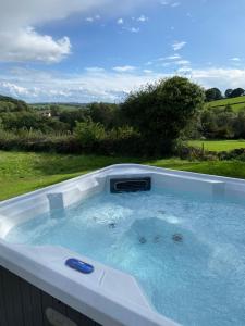 a jacuzzi tub with a view of a yard at Hazel Lodge luxury log cabin in South Wingfield