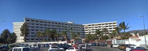 a large building with cars parked in a parking lot at Paraíso Maspalomas Experience in San Bartolomé