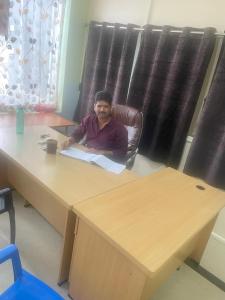 een man in een stoel aan een bureau bij Adith Grand in Tirupati