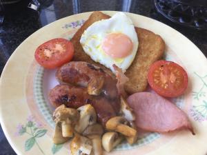 a plate of food with eggs sausage mushrooms and tomatoes at Private room in bright detached house in Salisbury