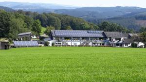 ein großes Haus mit einem grünen Feld davor in der Unterkunft Ferienwohnungen Bußmann in Herscheid