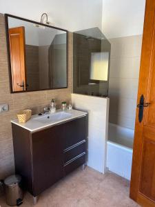 y baño con lavabo, espejo y bañera. en Hostal Espai Mediterrani, en Puebla de Vallbona