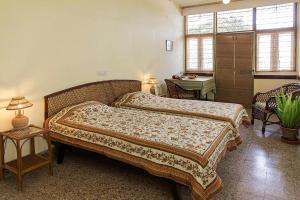 a bedroom with two beds and a table and a desk at The Green Hotel in Mysore