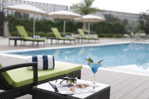 a table with a drink on it next to a pool at Golden Tulip Suites Gurgaon in Gurgaon