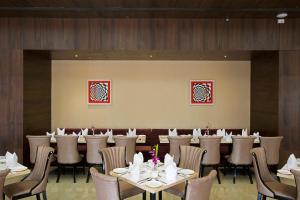 a dining room with tables and chairs in a restaurant at Golden Tulip Suites Gurgaon in Gurgaon