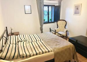 um quarto com uma cama, uma cadeira e uma janela em BellaLimone em Calatabiano