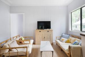 a living room with two couches and a tv at Pearl Beach House - 2 min to sand & sea - 2 semis in Pearl Beach