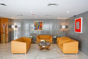 een lobby met 2 oranje stoelen en een tafel bij Golden Suites Gurugram by Inde Hotels in Gurgaon
