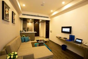 Golden Suites Gurugram by Inde Hotels في جورجاون: غرفة معيشة مع أريكة وتلفزيون