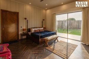 ein Schlafzimmer mit einem Bett und einer Glasschiebetür in der Unterkunft StayVista's The Sweet Life - 4BHK Farm-View Pet-Friendly Villa with Outdoor Pool in Sohna + 27 Fotos