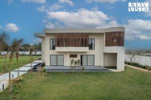 a house with a grassy yard in front of it at StayVista's The Sweet Life - 5BHK Farm-View Pet-Friendly Villa with Outdoor Pool in Sohna