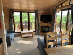 a living room with a fireplace and a television in a cabin at Hazel Lodge luxury log cabin in South Wingfield