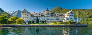 a large house on the water in front of mountains at Balestrand Fjordapartments Holmen 19A in Balestrand