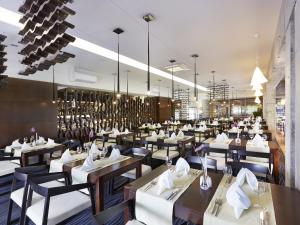 un restaurante con mesas de madera y sillas con servilletas blancas en VacationClub – Royal Tulip Sand***** Apartament 431, en Kołobrzeg