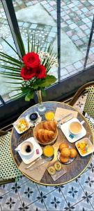 una mesa con desayuno y un jarrón con rosas en Les Glycines de Monchy- Chambres d'hôtes, en Monchy-Humières